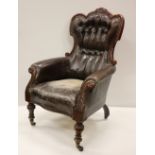 A Victorian carved walnut hide covered deep button back Armchair, on front turned legs.