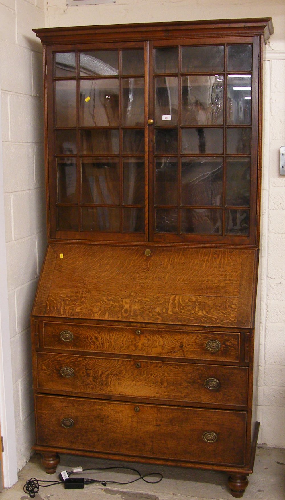 Georgian oak bureau bookcase, with glazed doors over the fall front and four drawers upon turned