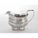 George IV silver cream jug, the half fluted body raised on four shaped feet, maker Thomas Wilkes