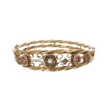 Victorian 9ct bangle set with two small rubies and a single diamond in an openwork setting, with