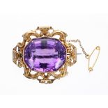 Large amethyst set brooch within a pierced yellow metal C-scroll surround, 19.1gm, 42mm wide