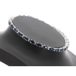Good 18k white gold sapphire and diamond line bracelet, with twenty-nine oval blue sapphires set