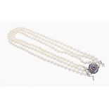 Good three strand pearl necklace with single ruby and diamond white metal cluster oval clasp, the