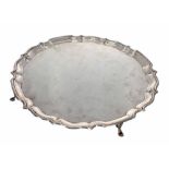 George V circular silver salver, with shaped rim raised on four feet, maker Carrington & Co.