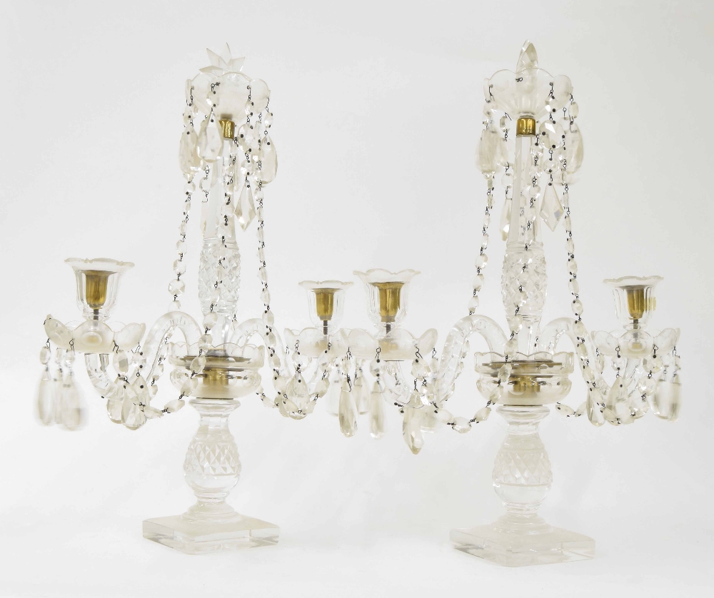 Pair of good cut glass twin branch candelabra, with prismatic drops upon baluster columns and square