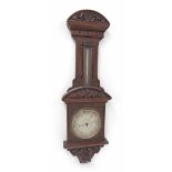 Mahogany aneroid barometer/thermometer, the 8" silvered dial within a foliate carved case surmounted