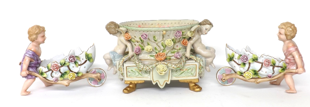 German style porcelain cherub centrepiece, raised on four feet, 7.5" high, 12" wide; together with a