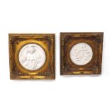 Pair of gilt framed faux marble circular plaques, one with putti playing musical instruments, the