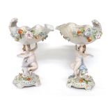 Pair of Dresden style porcelain cherub comports, the shell shaped comports with applied floral