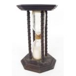 Antique hourglass within a stained wooden case, with four turned pillars and hexagonal stepped ends,