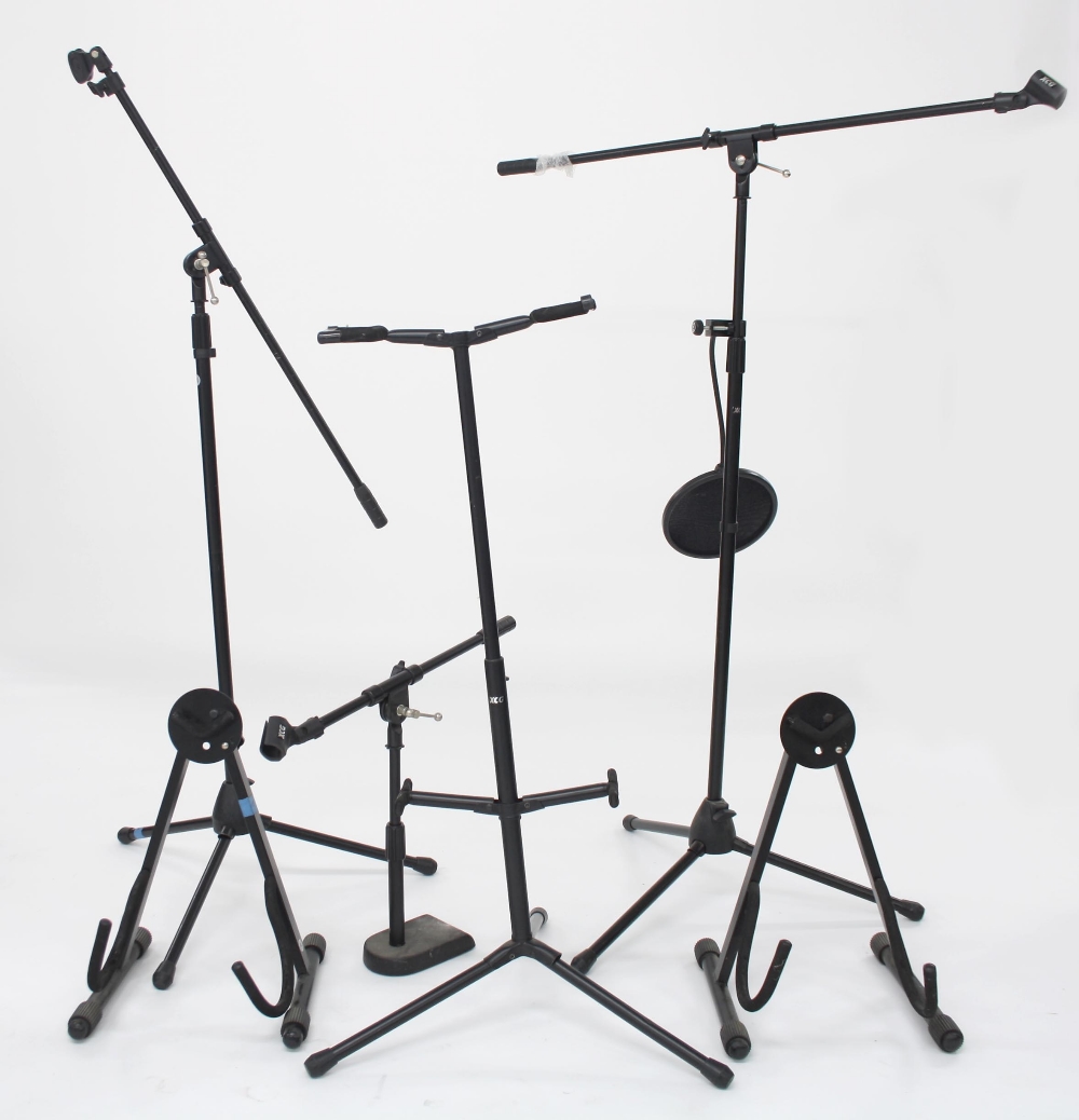 Three microphone stands, one with microphone pop shield; together with two A-frame guitar stands and