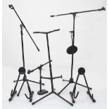 Three microphone stands, one with microphone pop shield; together with two A-frame guitar stands and