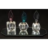 Cut Glass Scent Bottles Three miniature cut crystal fragrance bottles on mirrored display base,