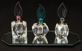 Cut Glass Scent Bottles Three miniature cut crystal fragrance bottles on mirrored display base,
