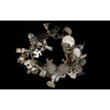 A Silver Charm Bracelet Loaded With Charms Approx 30 charms to include thimble, coins, flags,