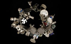 A Silver Charm Bracelet Loaded With Charms Approx 30 charms to include thimble, coins, flags,