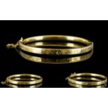 A 9ct Gold Hinged Bangle with Safety Chain, Stylised Floral Decoration to Outer Side of Bangle. c.