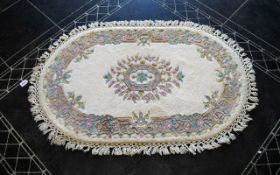 Oval Wool Rug Cream ground with grey, blue, green, pink and taupe floral and foliate border detail,