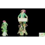 Chelsea Hand Painted Porcelain Figure of a Bare Footed Young Man Carrying a Large Empty Basket,