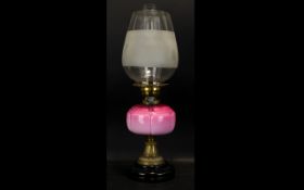 An Early 20th Century Oil Lamp Of Typical form with pink ombre glass reservoir,