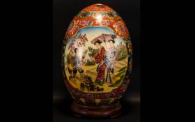 A Large Oriental Ceramic Egg. Raised On Circular Wooden Stand, The Body Decorated With Two Vignettes