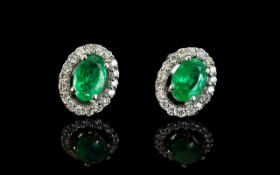 A Pair Of 14ct White Gold Emerald And Diamond Earrings Central oval emerald surrounded by round