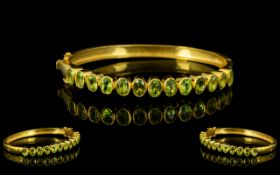 Peridot Oval Hinged Bangle, a row of oval cut peridots totalling 6cts, bezel set, vertically,