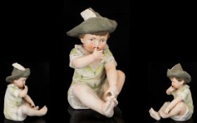 German Bisque Piano Doll Modelled in the form of an infant boy in feathered hat, gilt trim