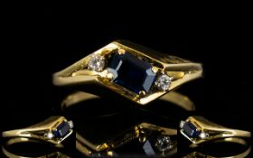 14ct Gold Sapphire And Diamond Dress Ring Set with central step cut sapphire between two round cut