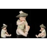 German Bisque Piano Doll Modelled in the form of an infant boy in feathered hat,