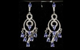 Tanzanite and Zircon Chandelier Earrings, each earring having a fringe of pear cut tanzanites on a