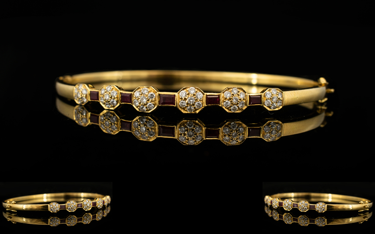 An 18ct Gold Diamond And Ruby Set Bangle Hinged yellow gold bangle set with five calibre cut rubies