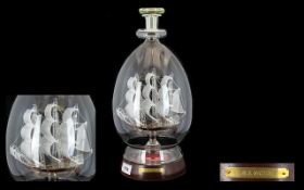 A Blown Glass Ship In Bottle Handblown figure, raised on circular wooden base in the form of H.M.