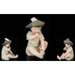 German Bisque Piano Doll Modelled in the form of an infant boy in feathered hat, gilt trim