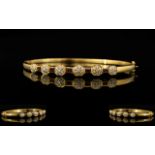An 18ct Gold Diamond And Ruby Set Bangle Hinged yellow gold bangle set with five calibre cut