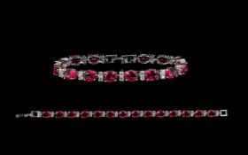 A Contemporary Silver Garnet And CZ Set Tennis Bracelet Of elegant form comprising fourteen oval