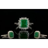 18ct White Gold Attractive Emerald And Diamond Cluster Ring Fully hallmarked, the central step cut