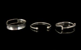 Three Silver Modernist Style Bangles Each marked for silver, comprising wide open buckle style cuff,