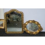 Two Gilt Edged Mirrors with bevelled glass. One in oval form decorated with cherubs, 53 x 48 cm.