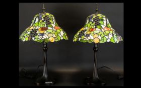 A Pair Of Reproduction Tiffany Style Table Lamps Each raised on black cast metal base with shaped