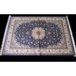 A Large Woven Silk Carpet Keshan rug with beige ground and blue border with traditional floral and