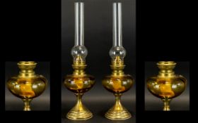 A Pair Of Antique Oil Lamps Two brass oil lamps of traditional form with amber glass body,
