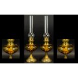 A Pair Of Antique Oil Lamps Two brass oil lamps of traditional form with amber glass body,