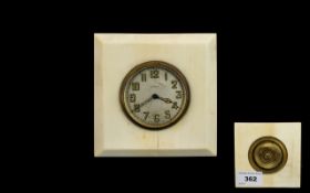 An Early 20th Century Travel Clock Square form clock set in cream cellulose, brass mount with