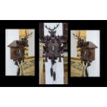 A Black Forest Cuckoo Clock, of typical form. With two weights and a stag and leaf pediment.
