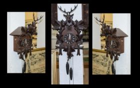 A Black Forest Cuckoo Clock, of typical form. With two weights and a stag and leaf pediment.