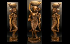 A Modern Carved Floor Standing Indonesian Figure In the form of a semi clad maiden carrying fruits.