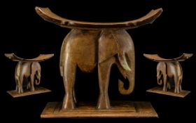 A Large African Carved Figural Elephant Stool with a concave seat raised on the back of an elephant