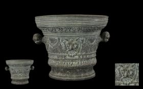 An Antique Bronze Mortar of typical form with moulded form and lion mask decoration. With twin
