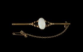 An Antique 9ct Gold Bar Brooch set with central oval milk opal. Fully hallmarked with safety chain.